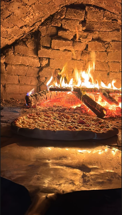 Pizza artesanal assando no forno a lenha